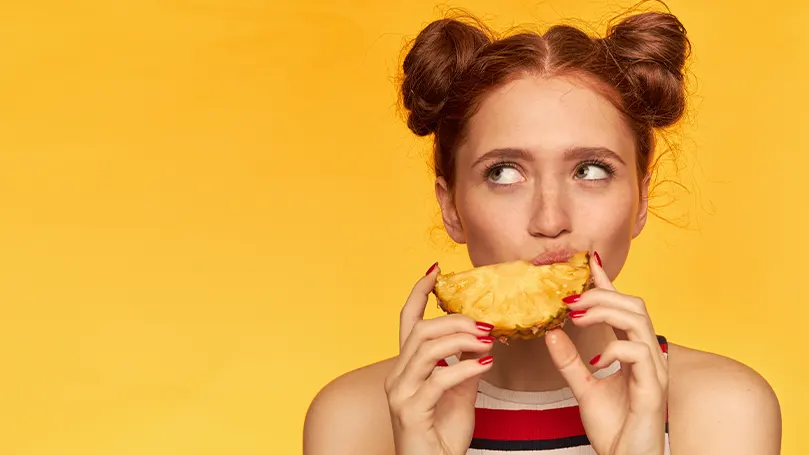 An image of a woman eating a pineapple