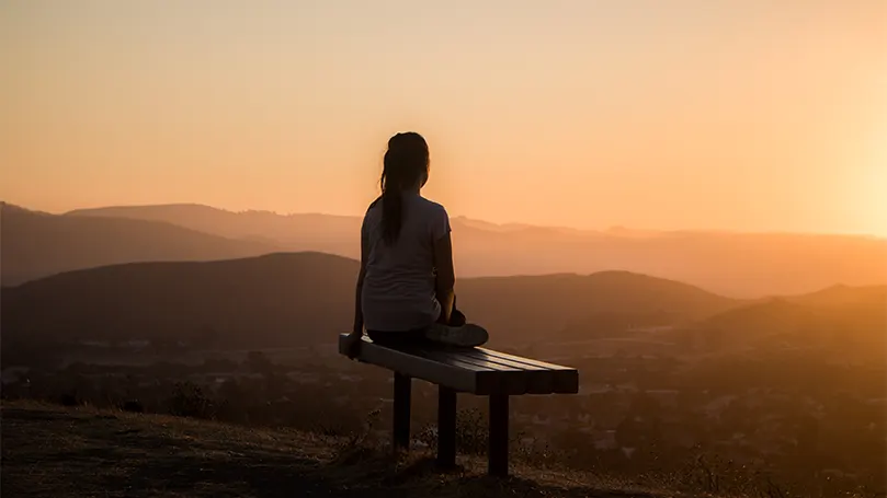 An image of a woman atop a mountain for anxiety relief