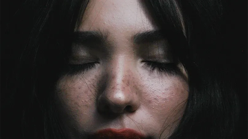 A close up image of a woman's face with her eyes closed