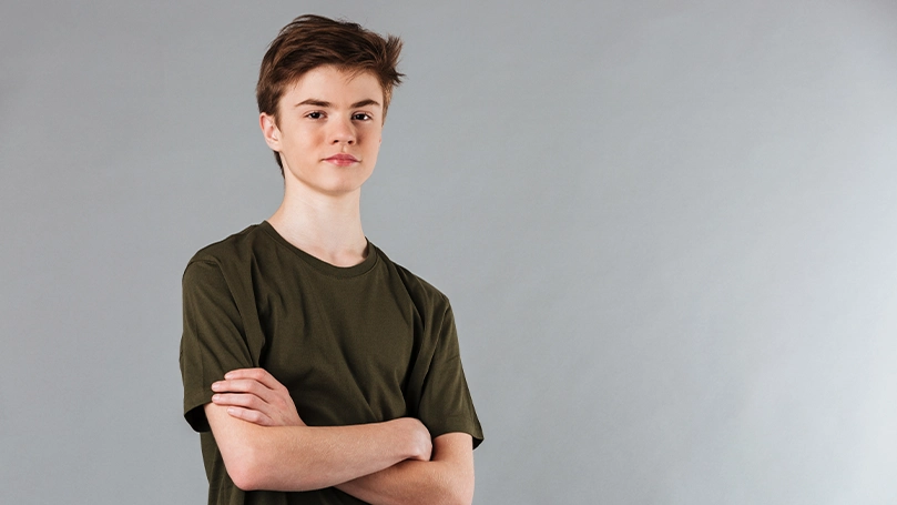 An image of a teenage boy with his arms crossed