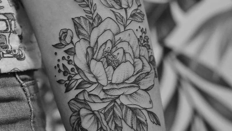 An image of a person's arm covered in a rose tattoo