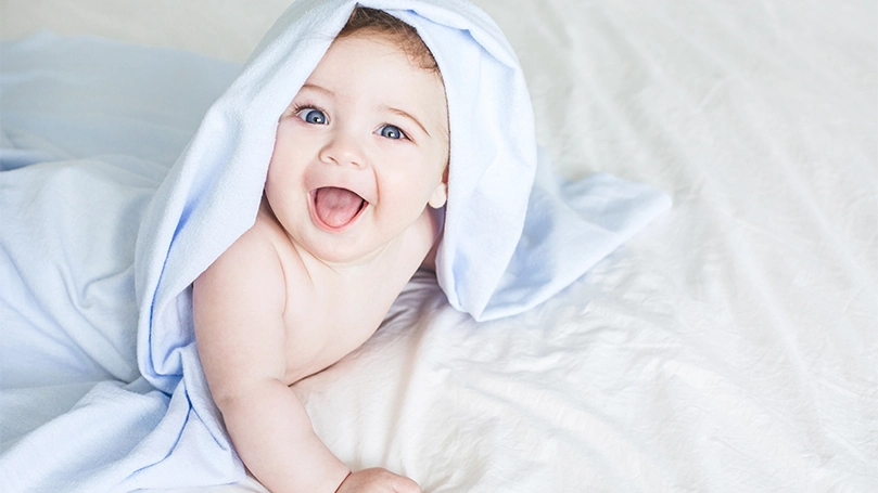 An image of a baby with a towel of their head