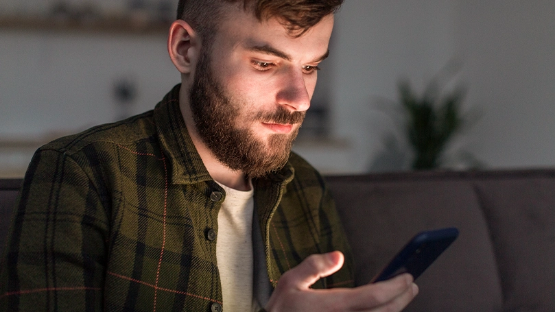 An image of a man looking at his phone before bed