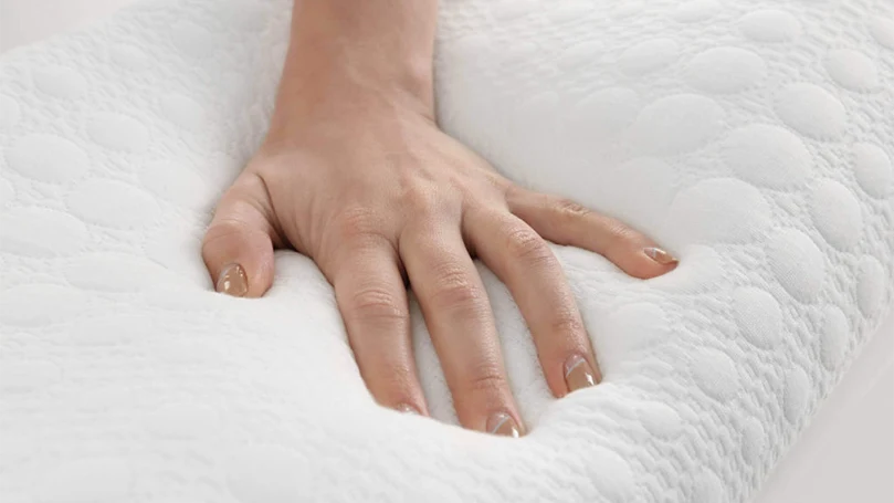 A female's hand pressing a memory foam mattress