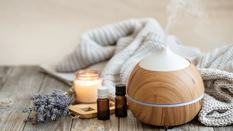 a diffuser on a table next to essential oils