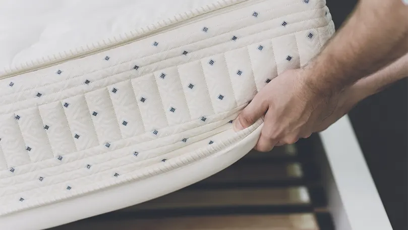 An image of a person lifting up a spring mattress