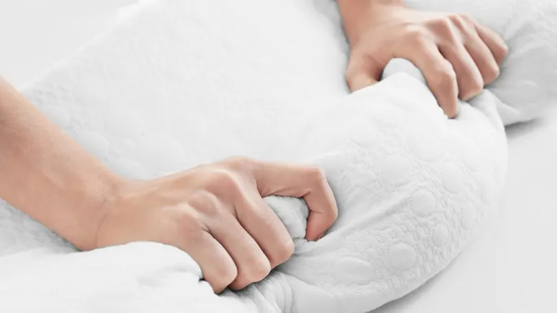 Hands squeezing a memory foam mattress topper