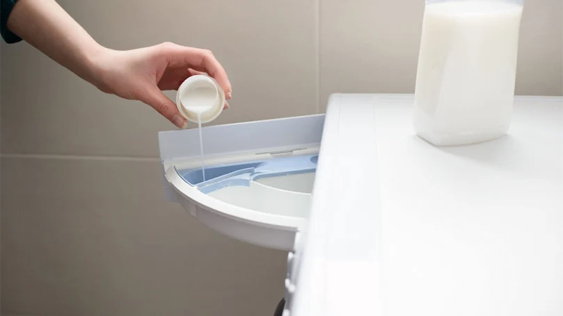 pouring a fabric softener in a washing machine