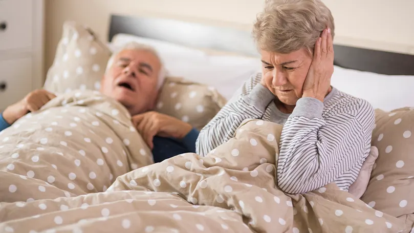 An image of an old couple in bed where the husband snores and keep the wife awake