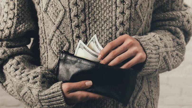 a man holding a wallet with money