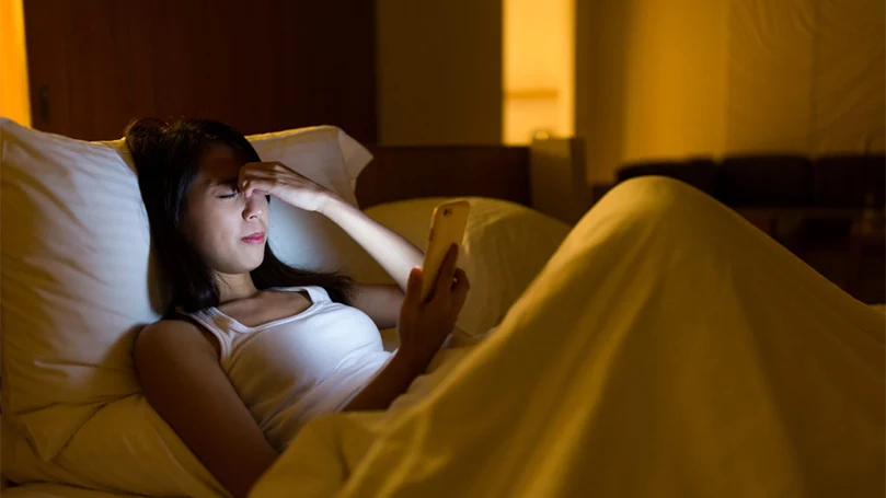 an image of a woman in a bed having a migraine headache