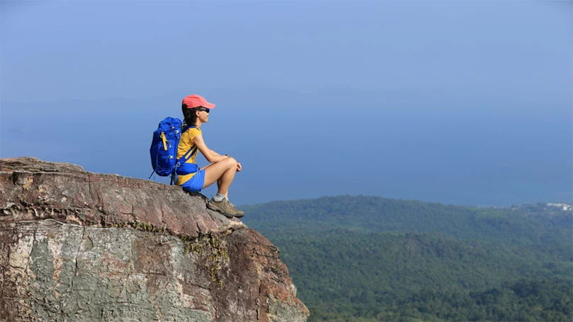 a woman sitting on the edge of a rock