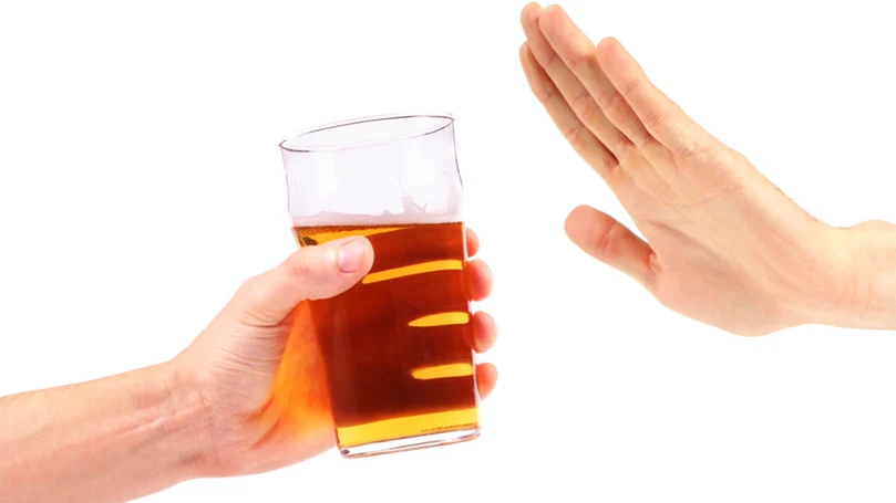 A hand refusing to take a glass of alcohol