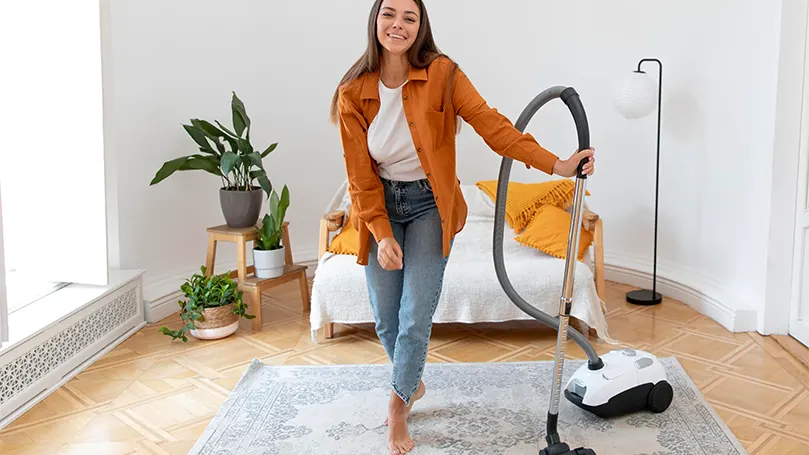 An image of a woman vacuuming her room