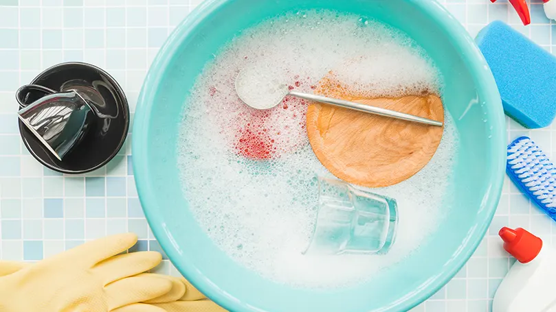 An image of different cleaning supplies submerged in soapy water