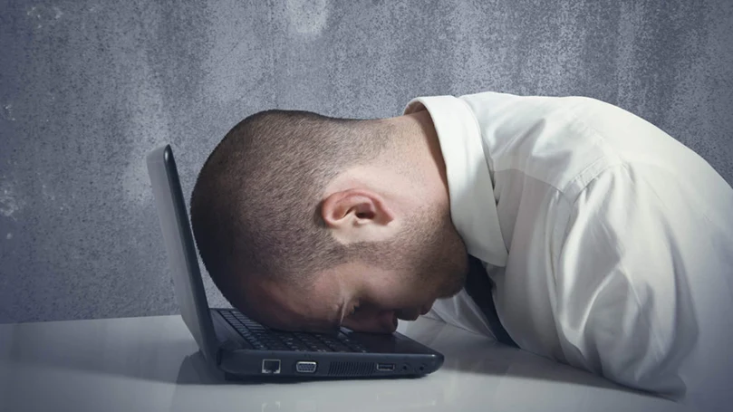 an image of a man sleeping on a laptop