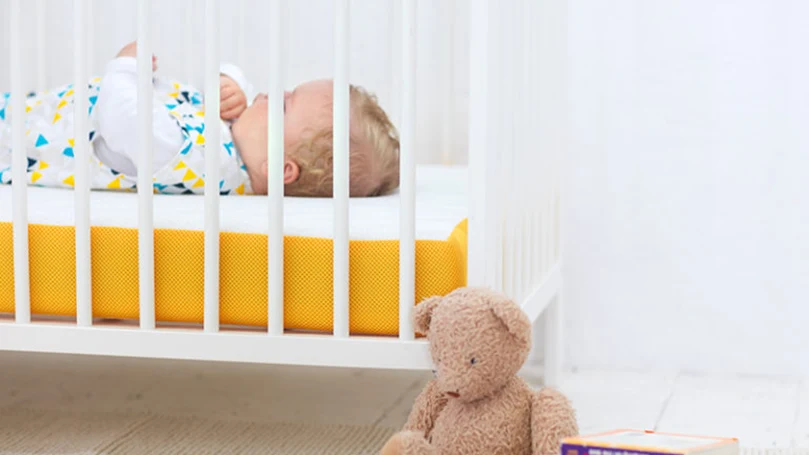 a child sleeps on an eve baby cot mattress