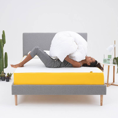 eve original mattress on bed with a girl on top holding a duvet