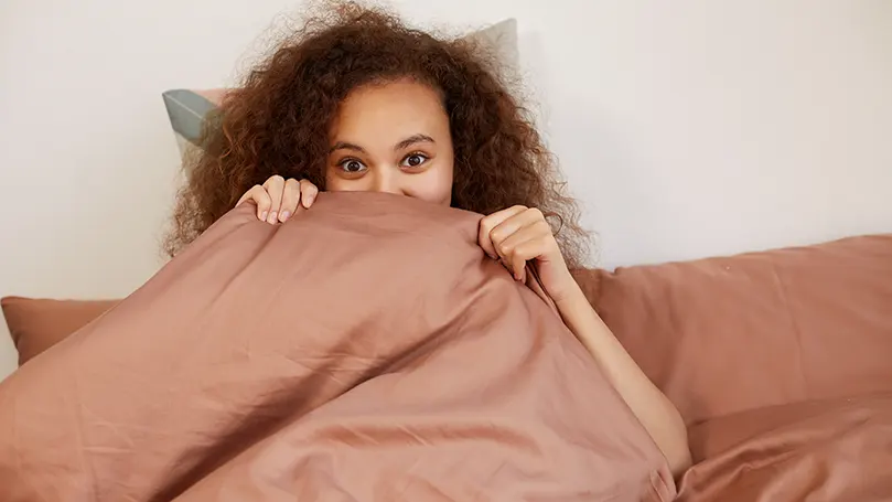 An image of a woman covered by a weighted blanket