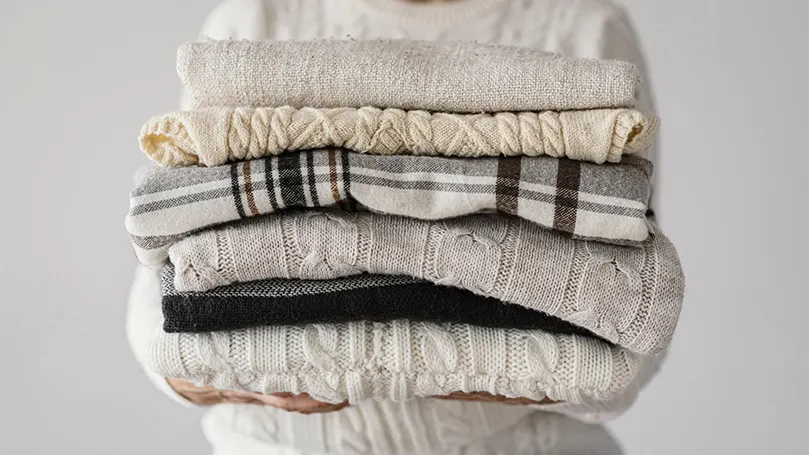 An image of a woman holding knitted blankets.