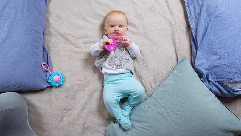 a baby laying on a bed next to many pillows