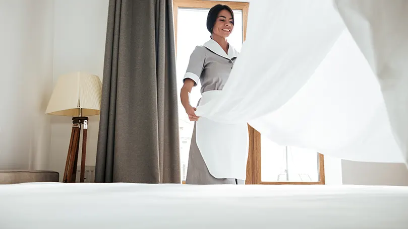 A maid changing bed sheets