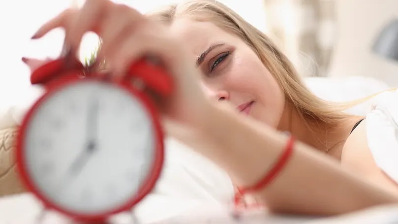 woman using an analogue alarm clock