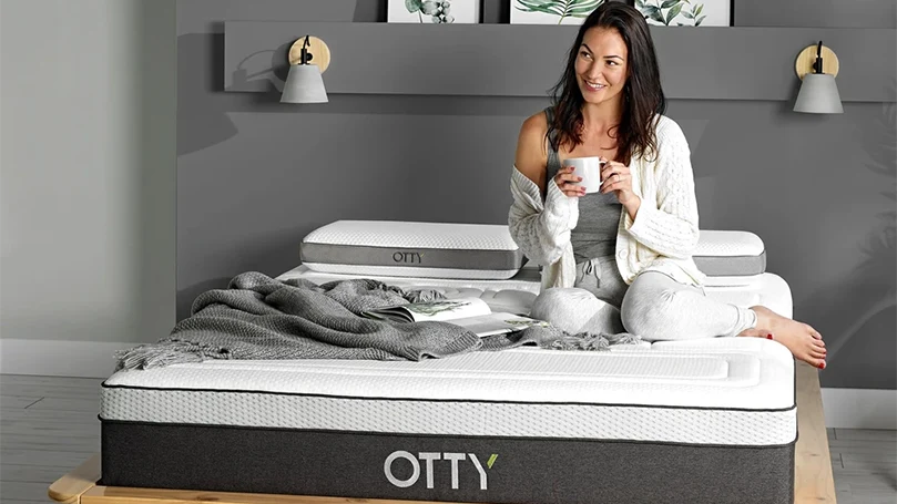 an image of a woman sitting on an otty pure hybrid bamboo & charcoal mattress
