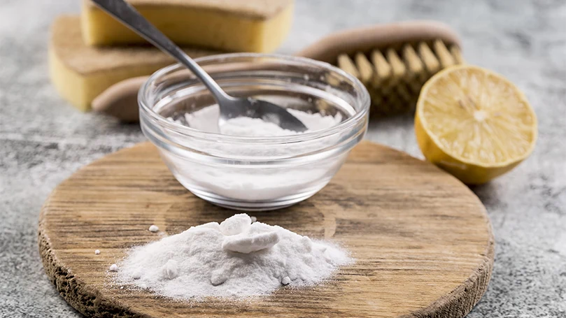 a baking soda powder in a small glass pot with a lemon next to it