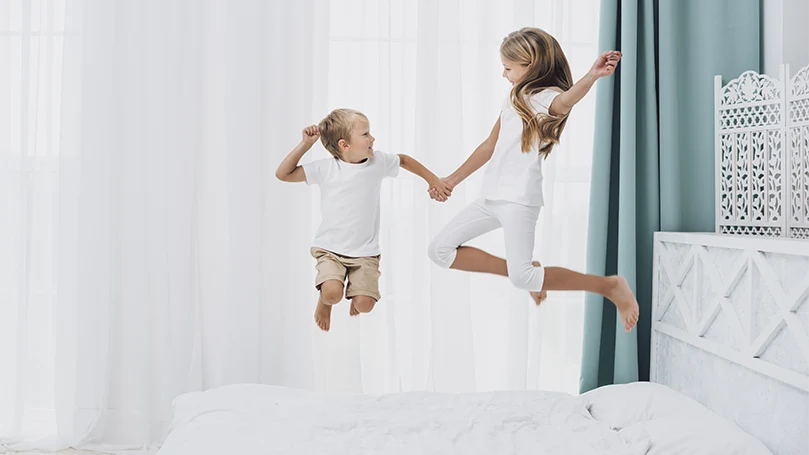 An image of kid jumping on a bed.