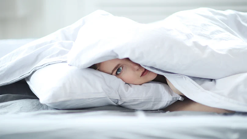 an image of a woman laying in a bed covered with a duvet