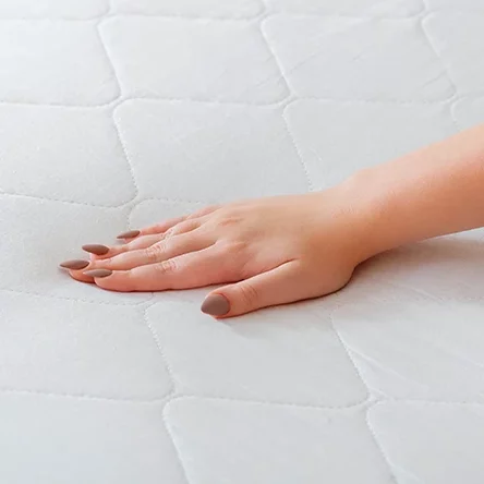a woman checking the firmness of a mattress