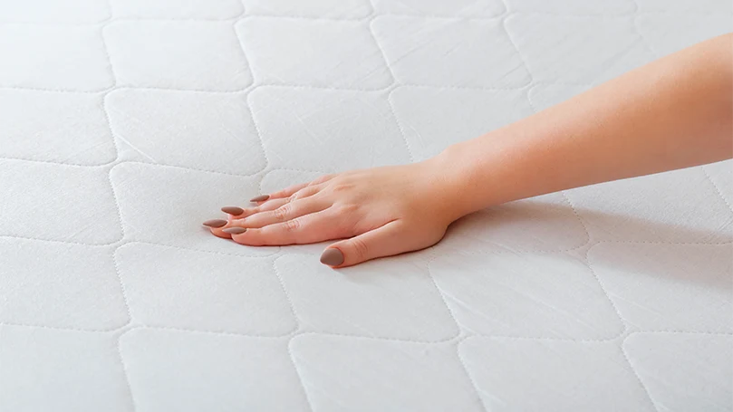 an image of a woman checking the firmness of a mattress