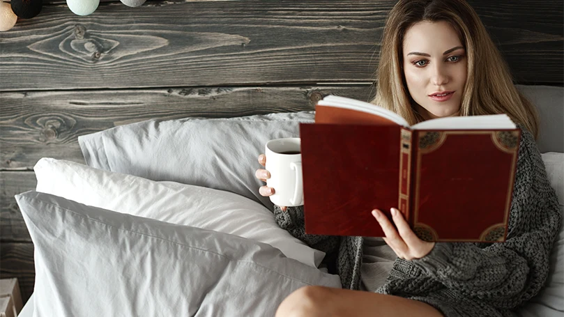a-woman-reading-a-book-in-bed