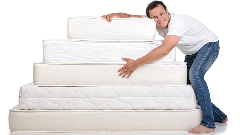 an image of a man holding multiple mattresses