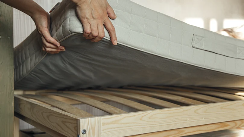 an image of a man lifts up a mattress from a bed frame