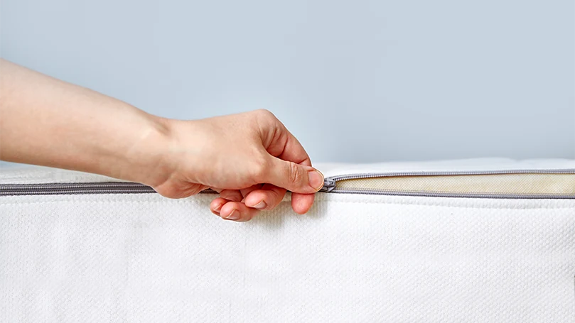 an image of a man removing a removable cover from a mattress