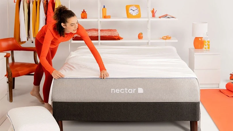 an image of a woman putting on sheets on nectar hybrid mattress