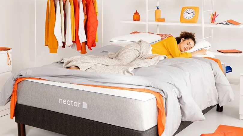 an image of a woman laying down in a nectar hybrid mattress in a bedroom