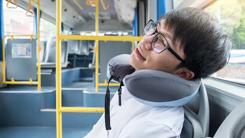 an image of a man sleeps with a cervical pillow in a bus