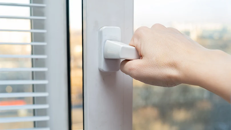 An image of a mans hand opening window.