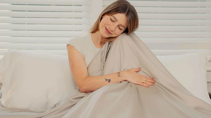 an image of a woman in a bed with Mela Chill Eucalyptus Weighted Blanket