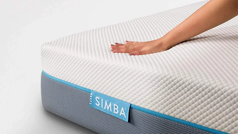 an image of a woman pressing the top layer of simba hybrid essential mattress