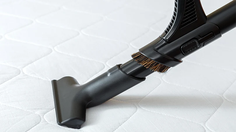 an image of cleaning a mattress with a vacuum cleaner