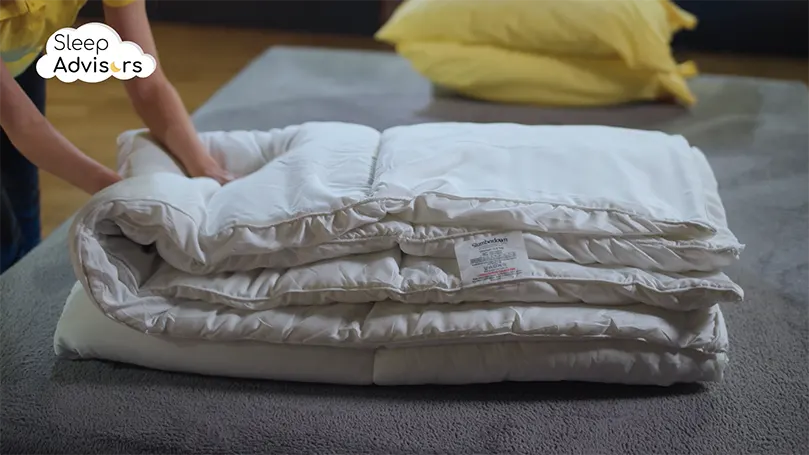 Slumberdown All Seasons duvet folded on a bed with our reviewer pressing it