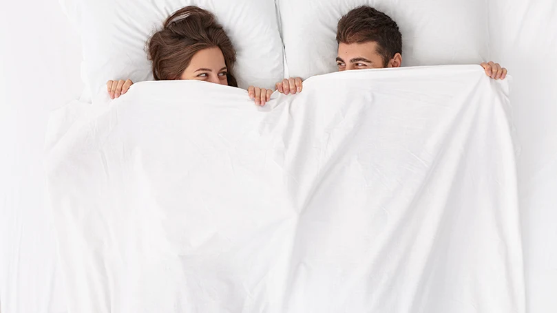 an image of a couple laying on a medium firm mattress