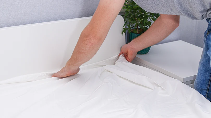 an image of a man changing a bed sheet