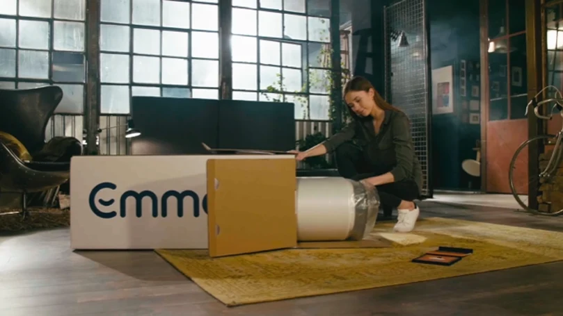 An image of a woman opens up Emma mattress delivery package.