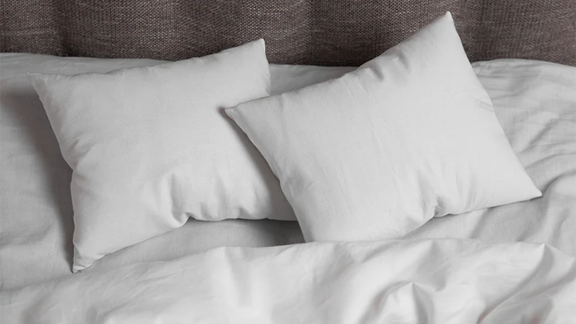 An image of 2 white pillows on a bed.