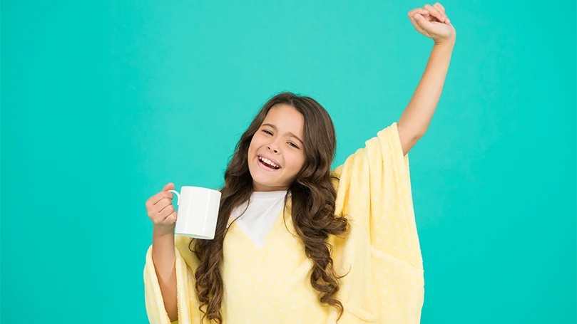 Featured image of A sleepy girl with a glass of milk before the bed time.